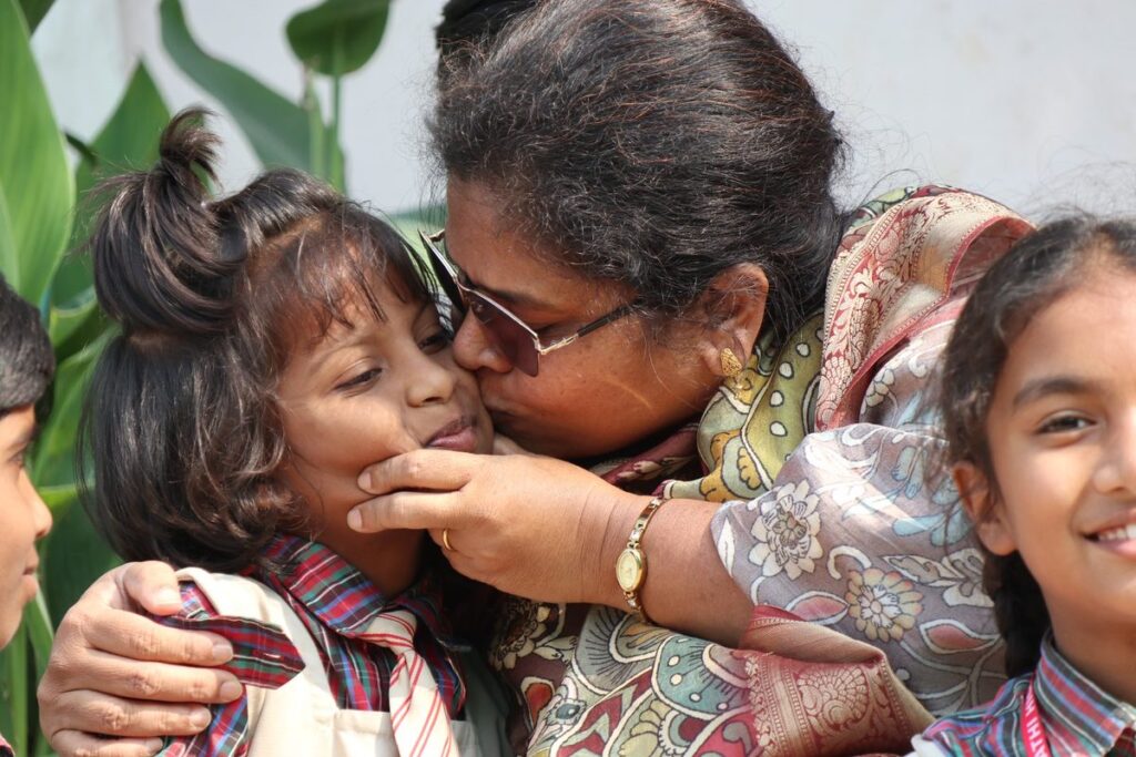 A caregiver kisses a young girl on the cheek