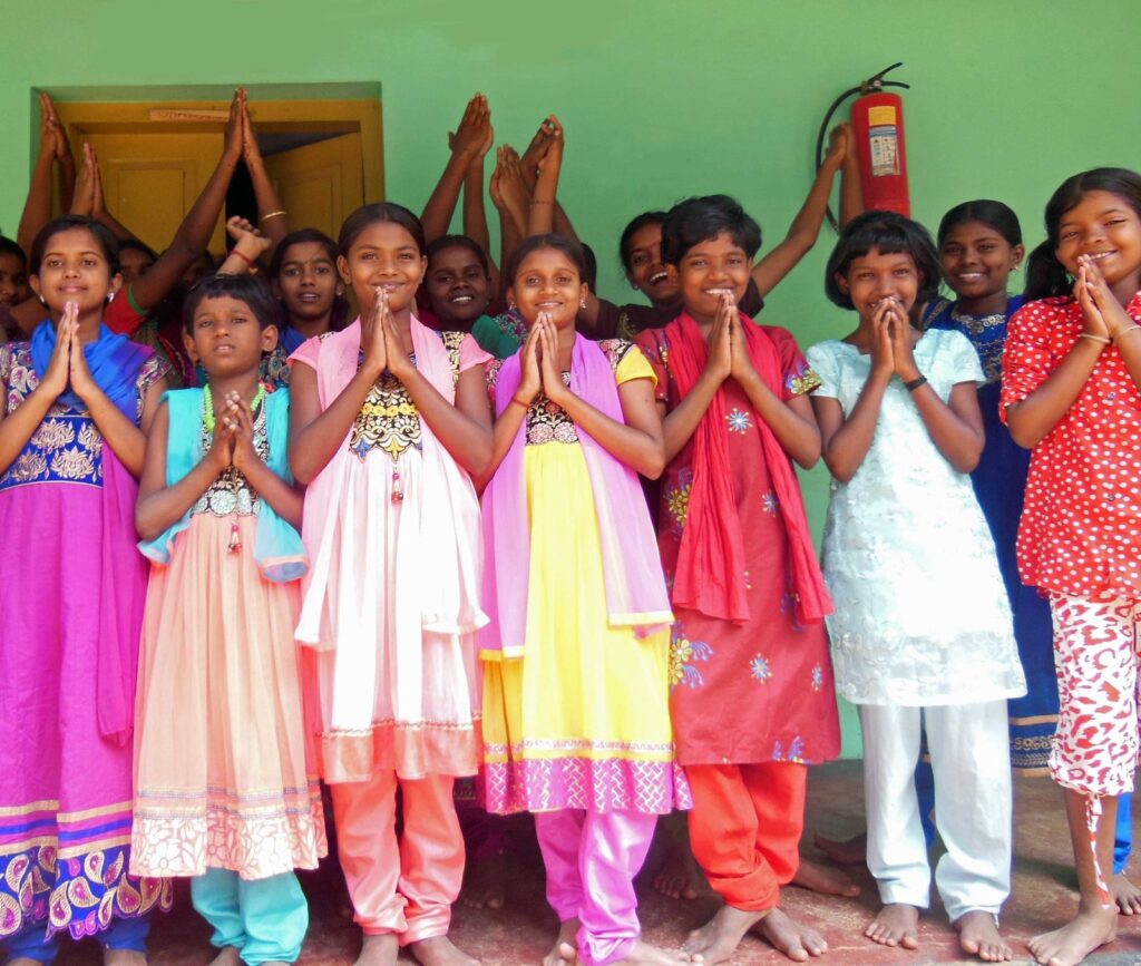 Girls of Fatima Home in colourful dresses greeting with folded hands