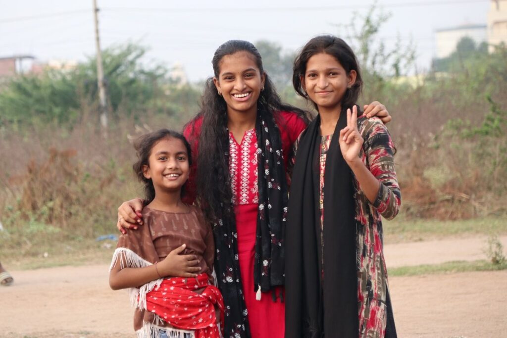 Three girls smile together outdoors